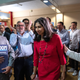 Suella Braverman, wearing a red dress, makes her way through a crowd.